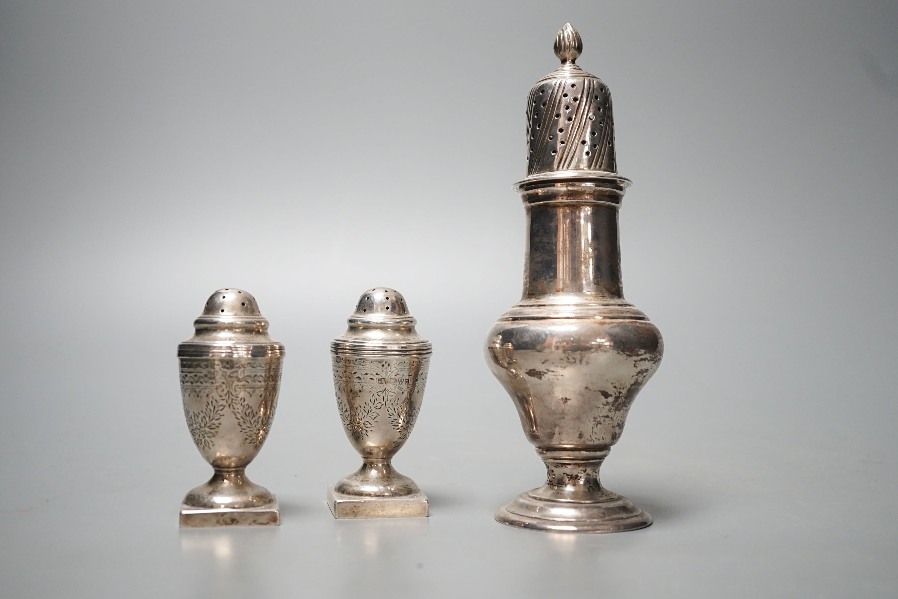 A late Victorian silver sugar caster, Charles Stuart Harris, London, 1899, 17cm and two silver early 20th century silver pepperettes, 7.5oz.